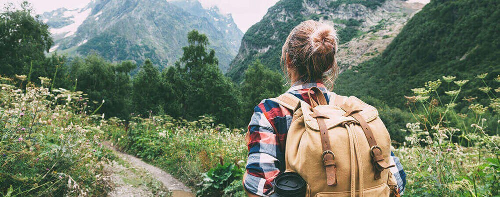 Žena hoda planinskom dolinom s ruksakom na leđima.